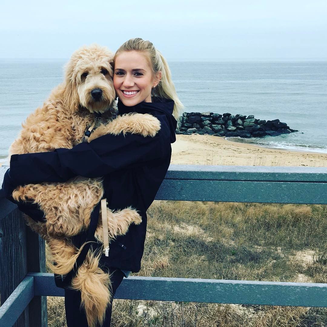 Lauren Burnham carrying her labradoolde with the view of the ocean in the backgorund