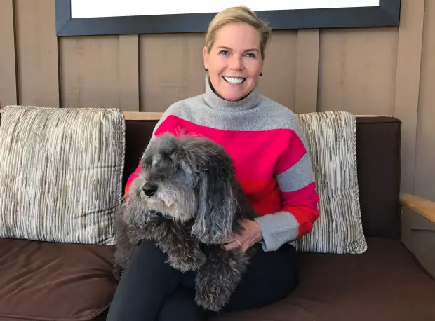 Pam Krueger sitting on the couch with her labradoodle sitting on her lap