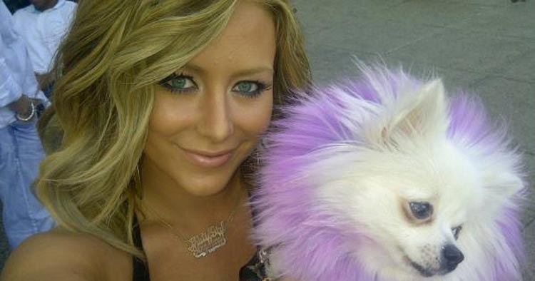 Aubrey Oday taking a selfie while carrying her Pomeranian with purple colored hair