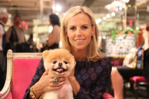 Tory Burch sitting on the chair with her Pomeranian in her lap