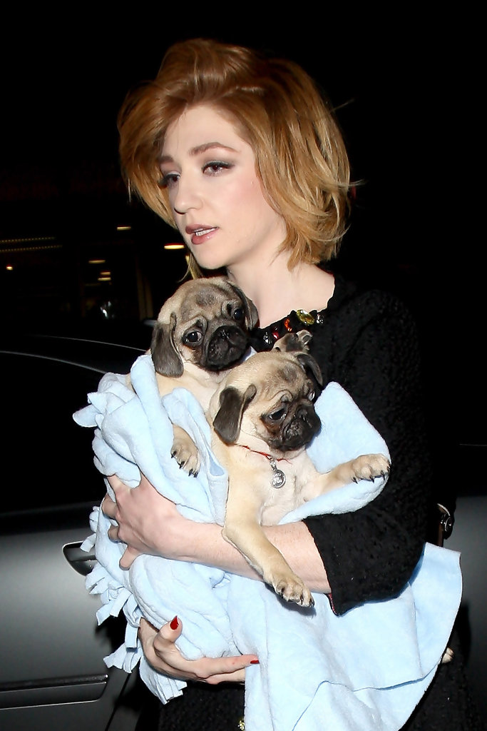 Nicola Roberts walking out of the car while carrying its two pug puppies wrapped in blue blanket