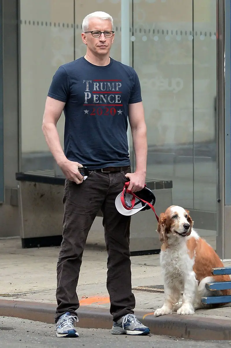 Anderson Cooper standing in the street with his Springer Spaniel sitting on the floor