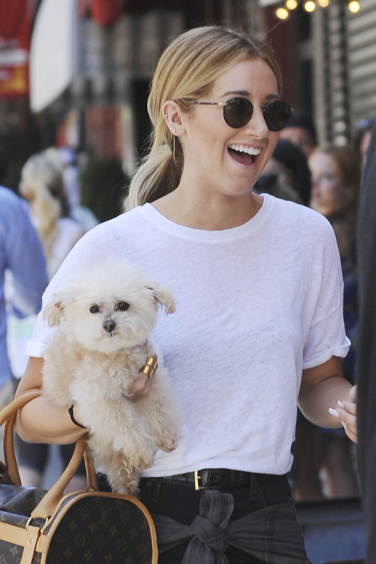 Ashely Tisdale excitedly walking in the street while carrying her Maltese.