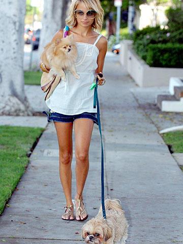 Nicole Richie walking in the street with her Shih tzu on a leash while carrying her Pomeranian in her arm