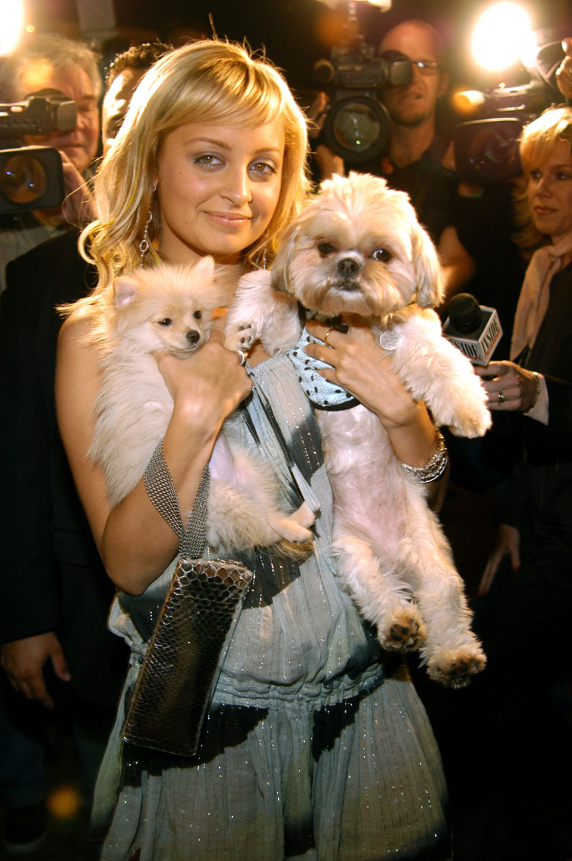 Nicole Richie with her Shih tzu and Pomeranian in her arms with cameras and reporters in the background