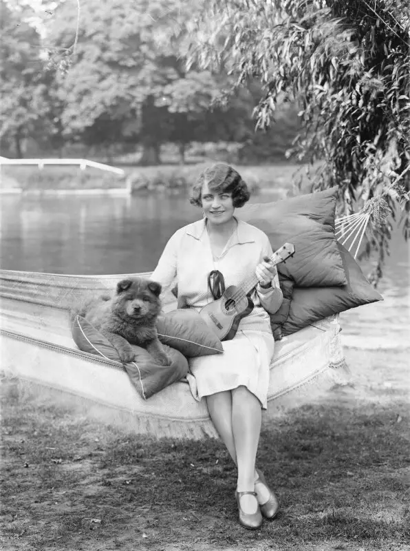 Madge Saunders sitting in a hammock with her Chow Chow puppy lying next to her on top of a pillow