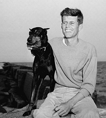 John F. Kennedy siting by the beach with hi Doberman