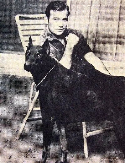 William Shatner sitting on the chair with his Doberman standing next to him