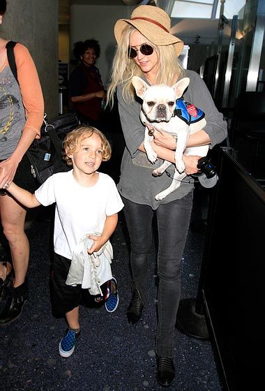 Ashlee Simpson walking with her family while carrying her French Bulldog