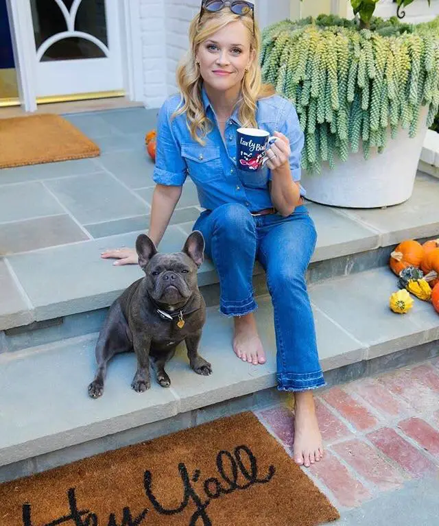 Reese Witherspoon sitting in the front porch next to her French Bulldog
