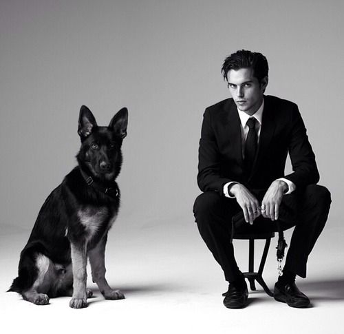 Dylan Rieder sitting on the chair with a German Shepherd dog sitting next to him