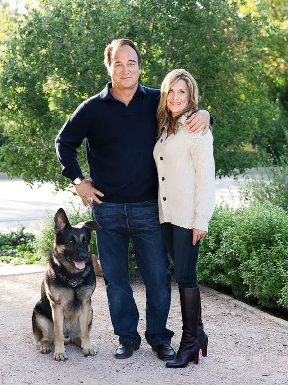 James Belushi with his wife and his German Shepherd sitting on the pavement next to them