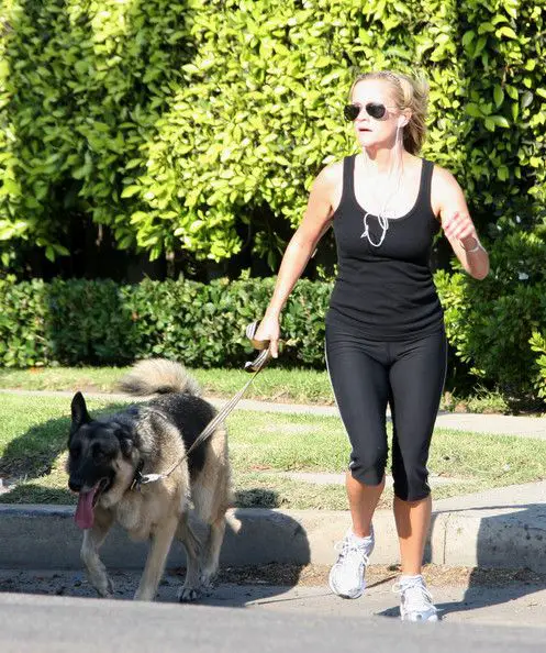 Reese Witherspoon running outdoors with her German Shepherd dog