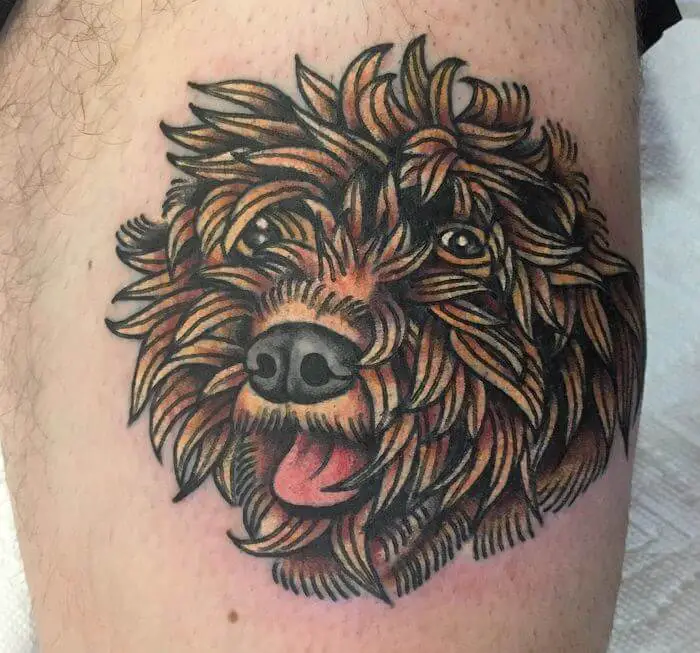 An artistic smiling face of a Goldendoodle tattoo on the leg