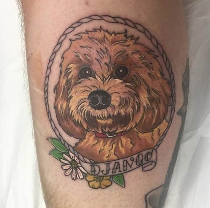 A red Labradoodle puppy inside a rope frame tattoo on the leg