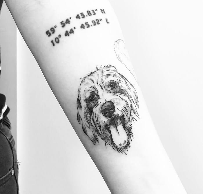 minimalist black and gray face of a Labradoodle while smiling with its tongue out tattoo on the forearm