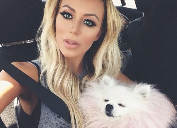 Aubrey Oday taking a selfie inside the car with her white Pomeranian