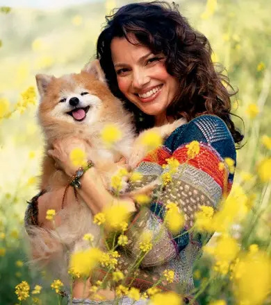 Fran Drescher in the field holding her smiling Pomeranian in her arms