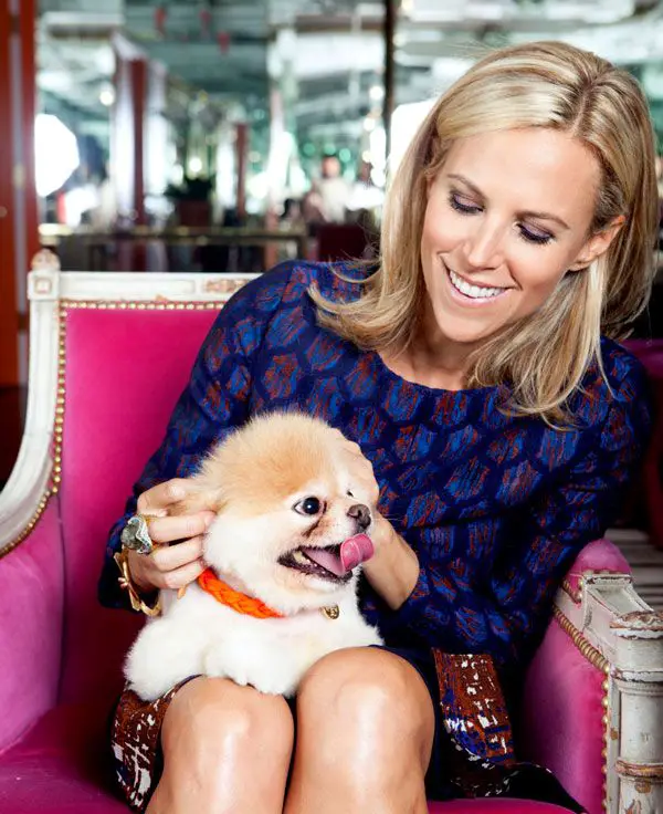 Tory Burch sitting on the chair while petting her Pomeranian in her lap