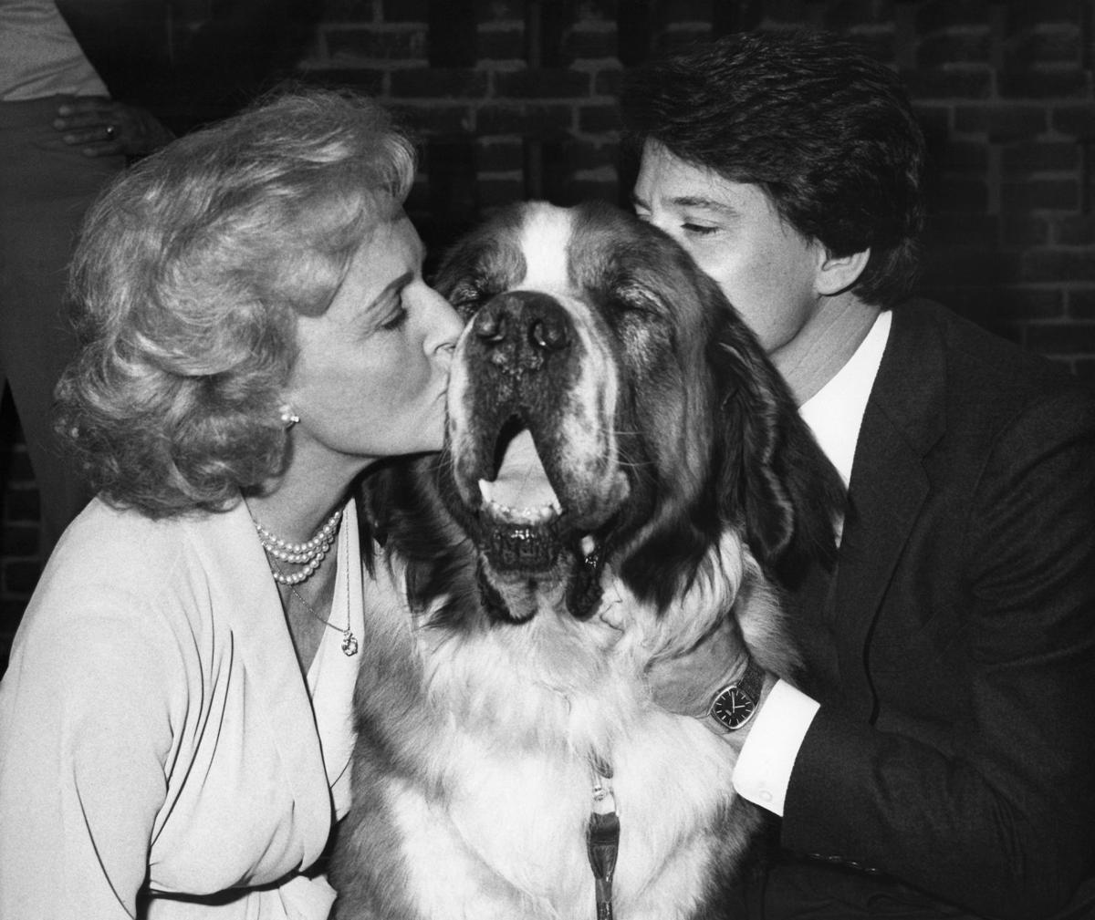 Betty White and a man kissing a St. Bernard in between them