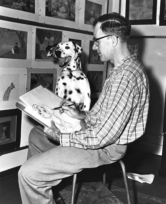 black and white photo of Dodie smith drawing his Dalmatian sitting next to him