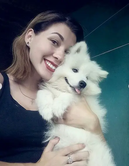 A woman holding her Samoyed puppy