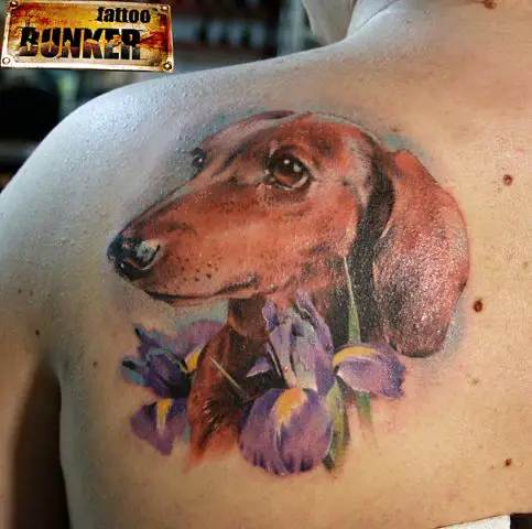 realistic brown Dachshund with purple flowers tattoo on the back of a woman