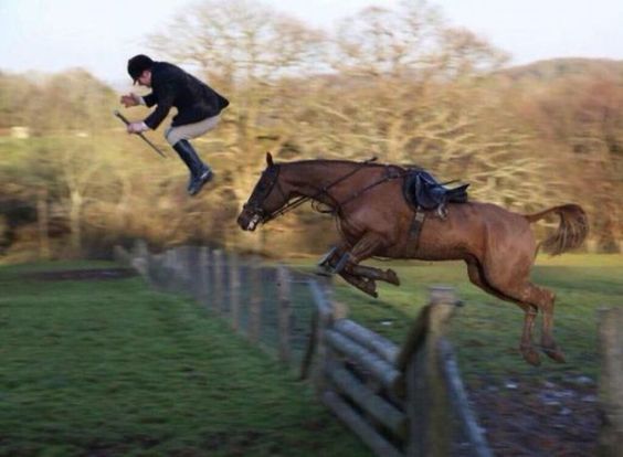A Horse jumping over the fence while its rider is on the air