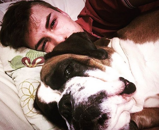 A man taking a selfie while lying on the bed with his Boxer