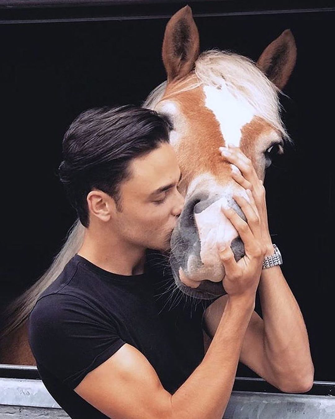 a man kissing the cheeks of a Horse
