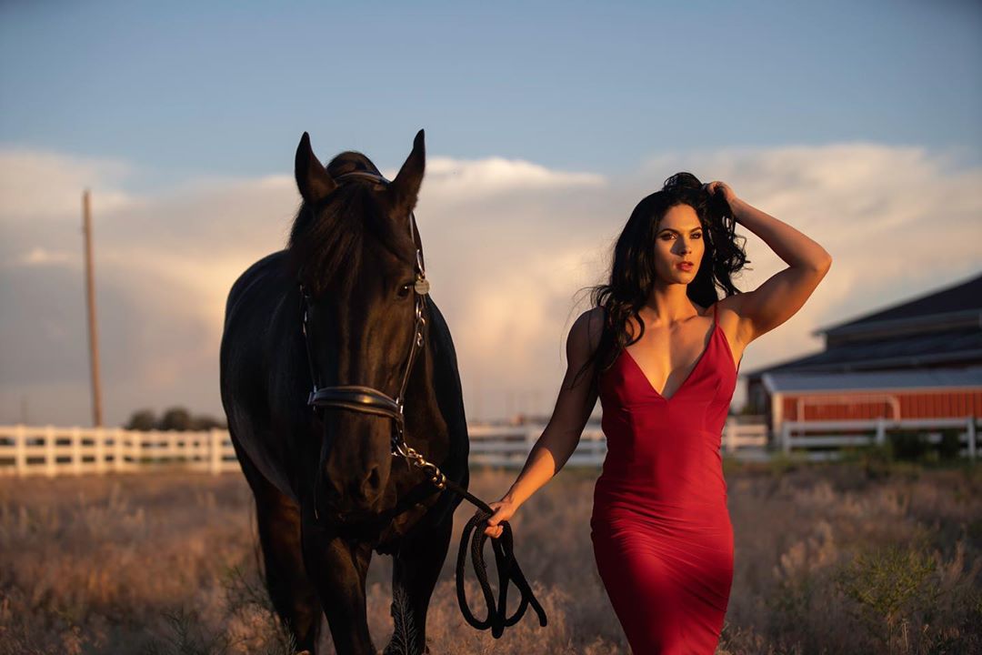 a woman walking in the field next to a Horse