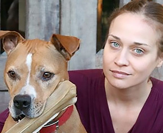 Fiona Apple with her Pitbull holding a bone treat in its mouth