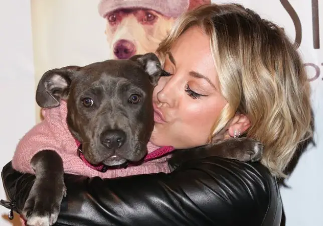 Kaley Cuoco kissing her pitbull while hugging it