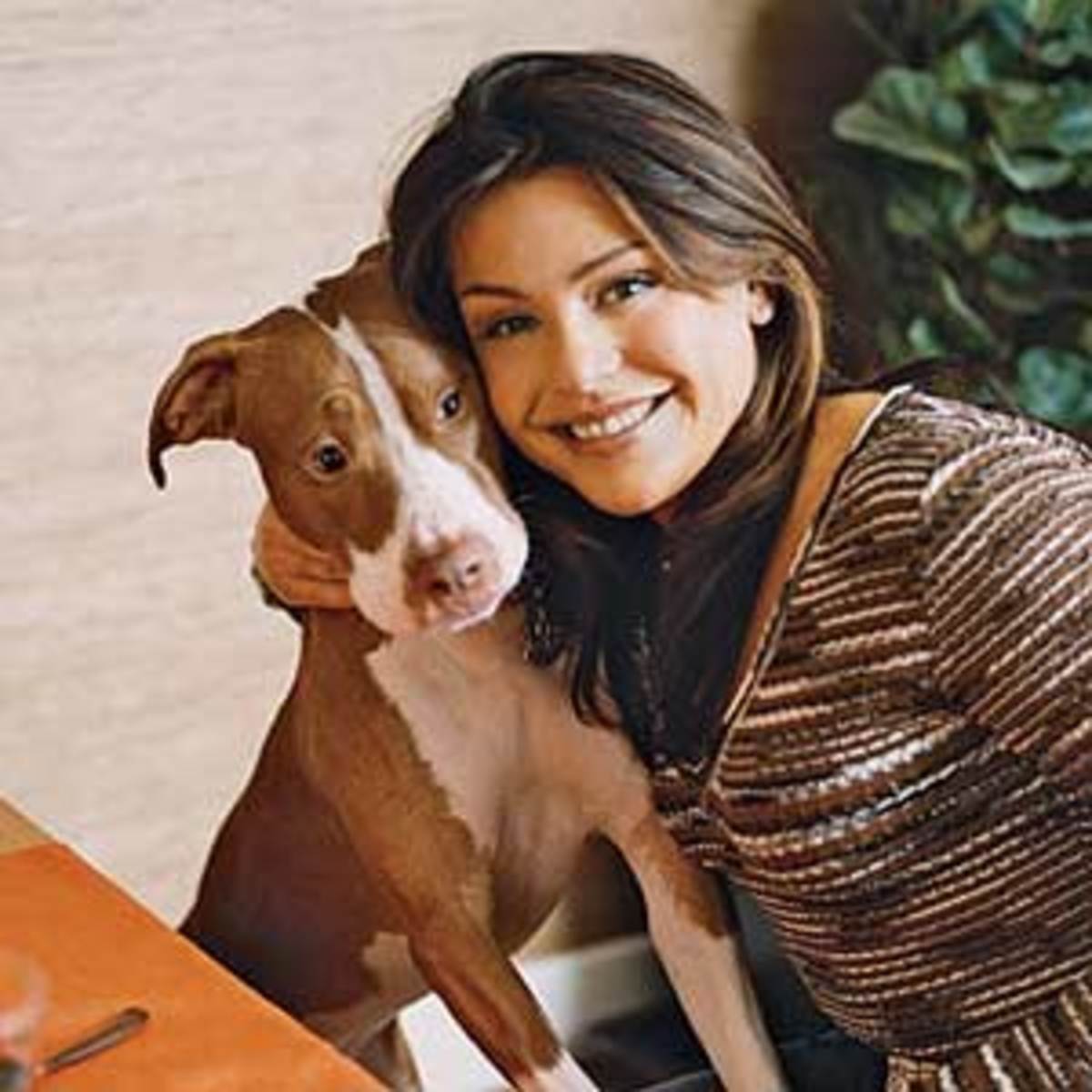 Rachael Ray sitting at the table while embracing her pitbull
