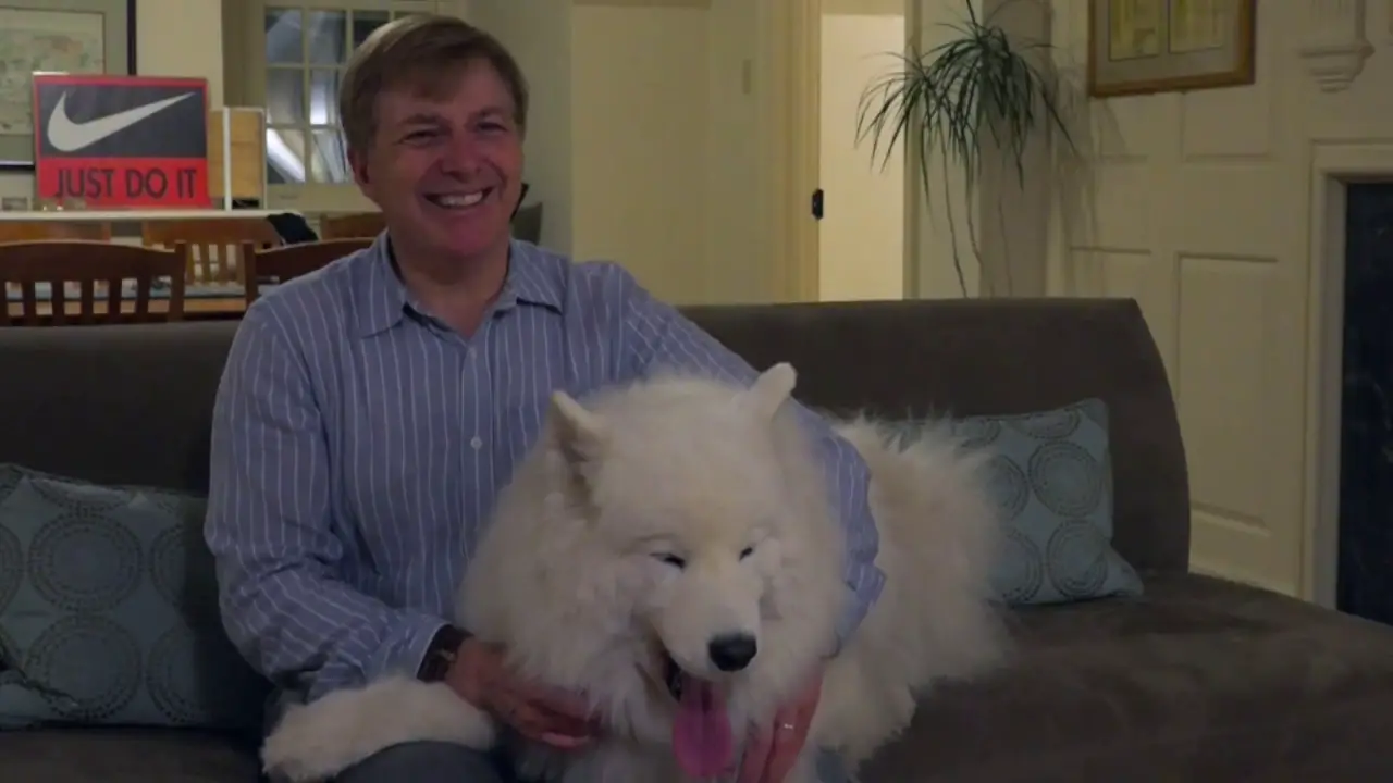 A David McCormick sitting on the couch with his Samoyed
