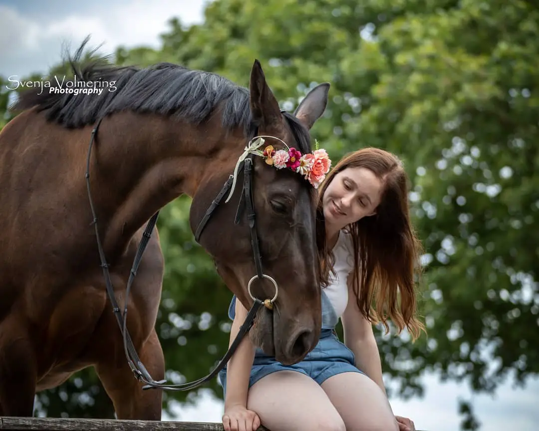 girl sitting with the horse's face beside her