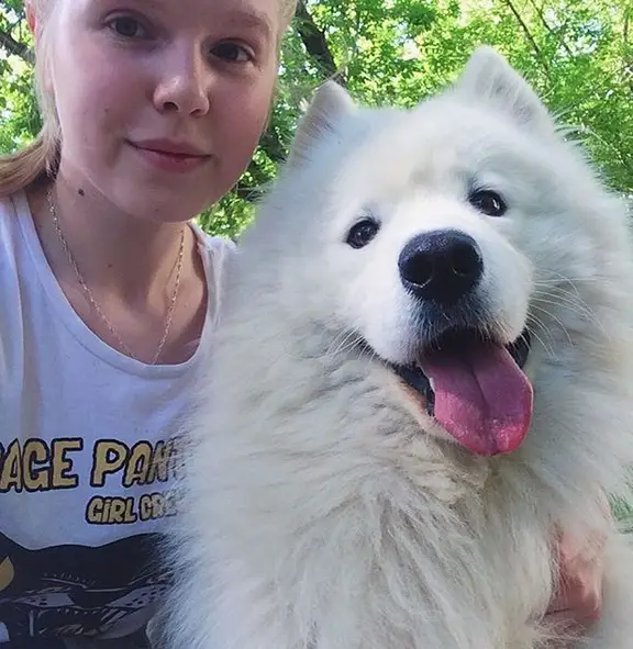 A woman taking a selfie with her Samoyed