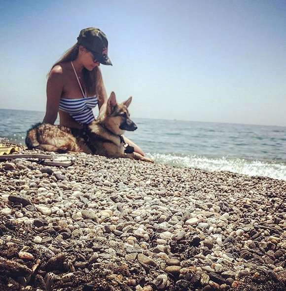 A German Shepherd lying by the seashore with a woman