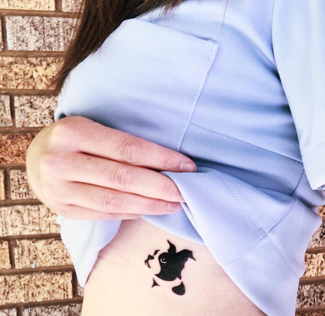 minimalist looking up face of a Boston Terrier tattoo on the side of the girl's body