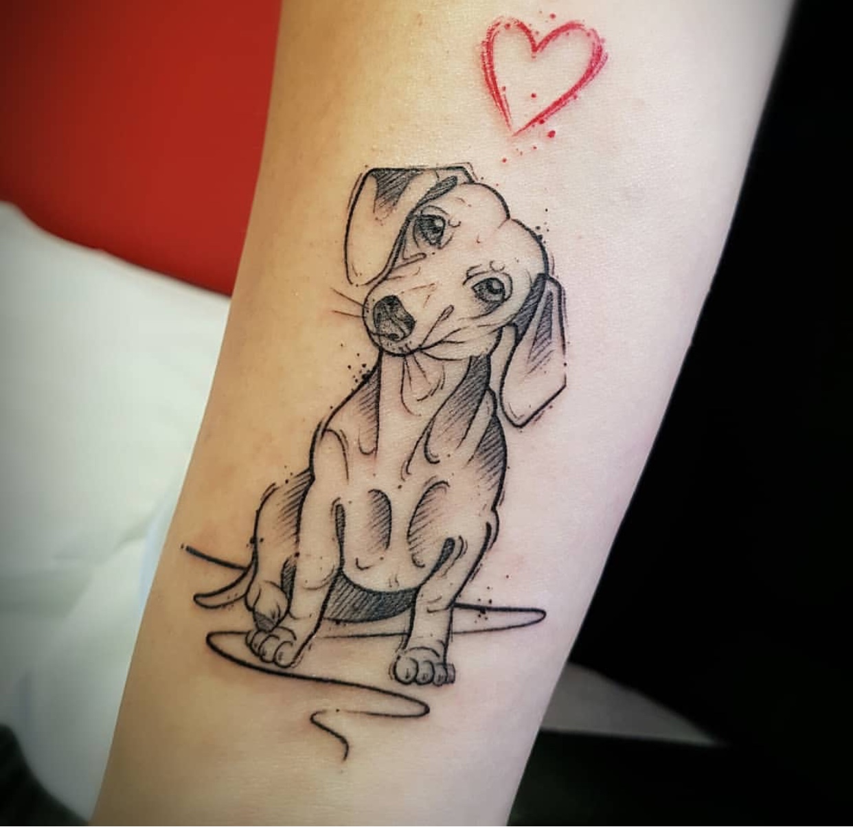 outline of Dachshund with red heart tattoo on arm