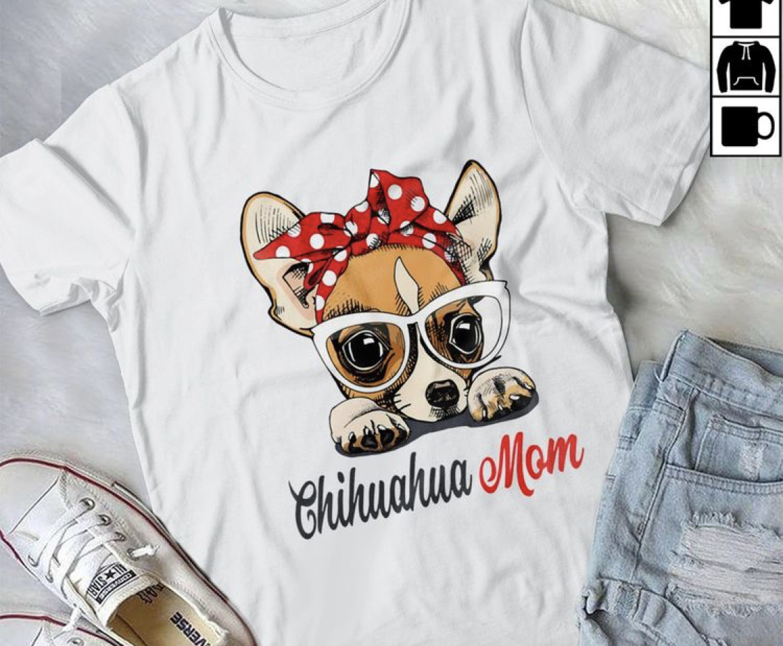 a white t-shirt printed with chihuahua wearing red headband and words chihuahua mom on the bed with a pair of shoes and denim shorts