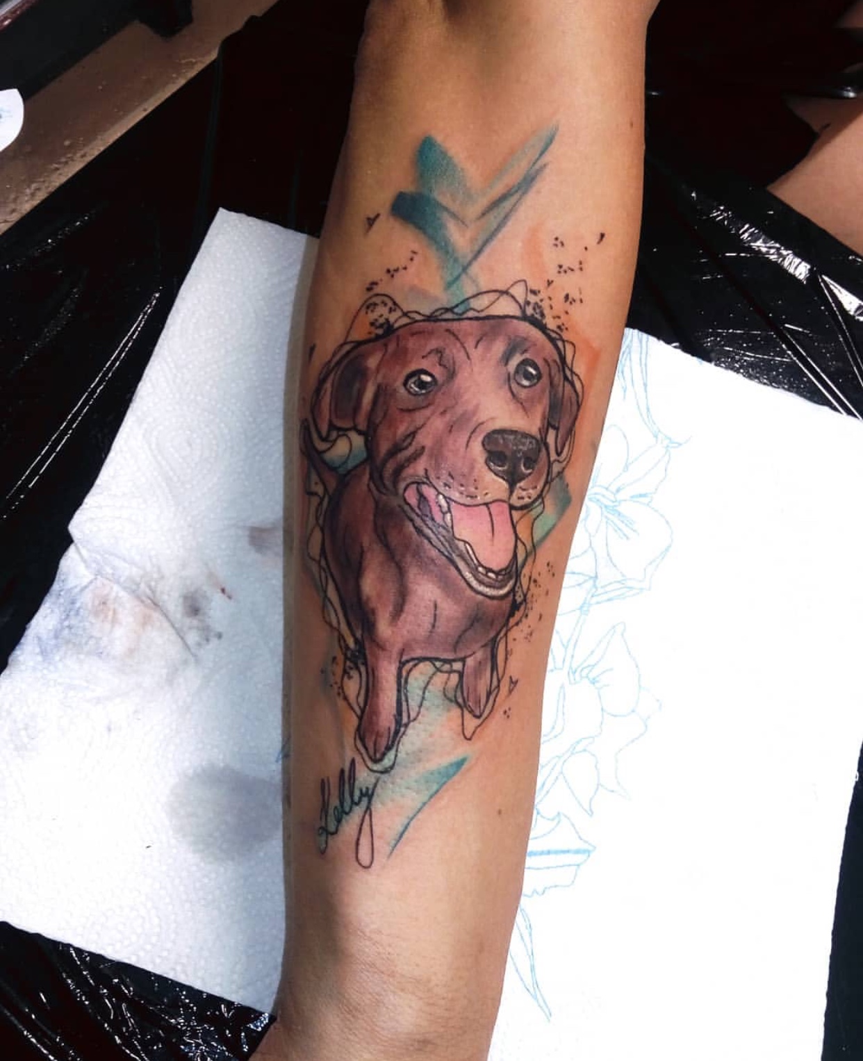 a chocolate brown artistic tattoo of a Labrador Retriever on the forearm