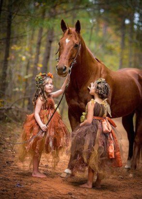 two little girls in their fairy dress with a horse in the forest