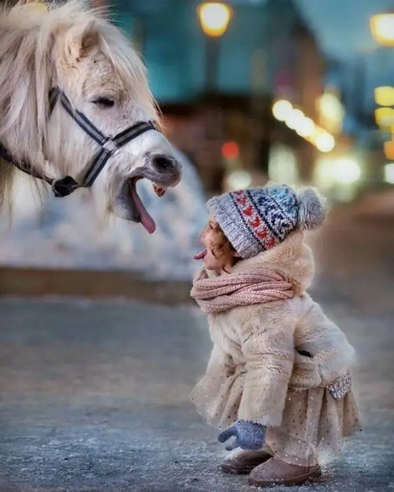 a little girl sticking its tongue out in front of horse sticking its tongue out too