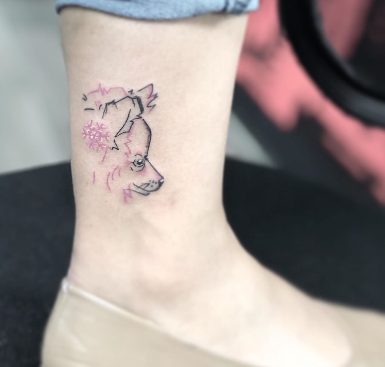 outline of Pomeranian with black and white colors tattoo on the ankle