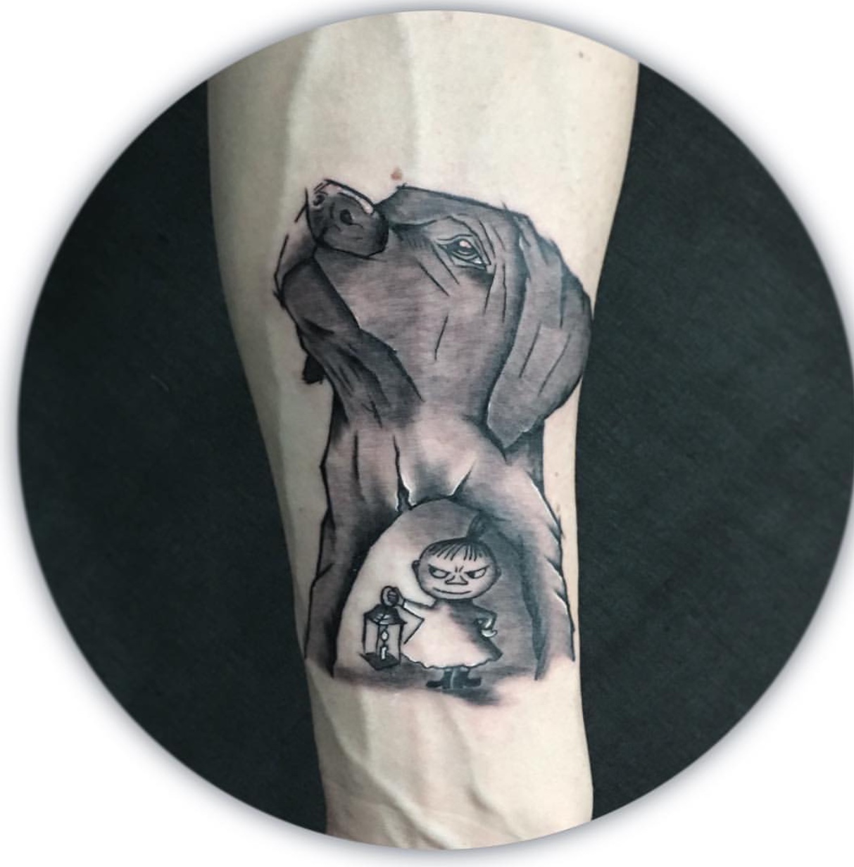 black and gray sketched face of a Labrador Retriever with an animated kid holding a lamp design on its neck tattoo on the forearm