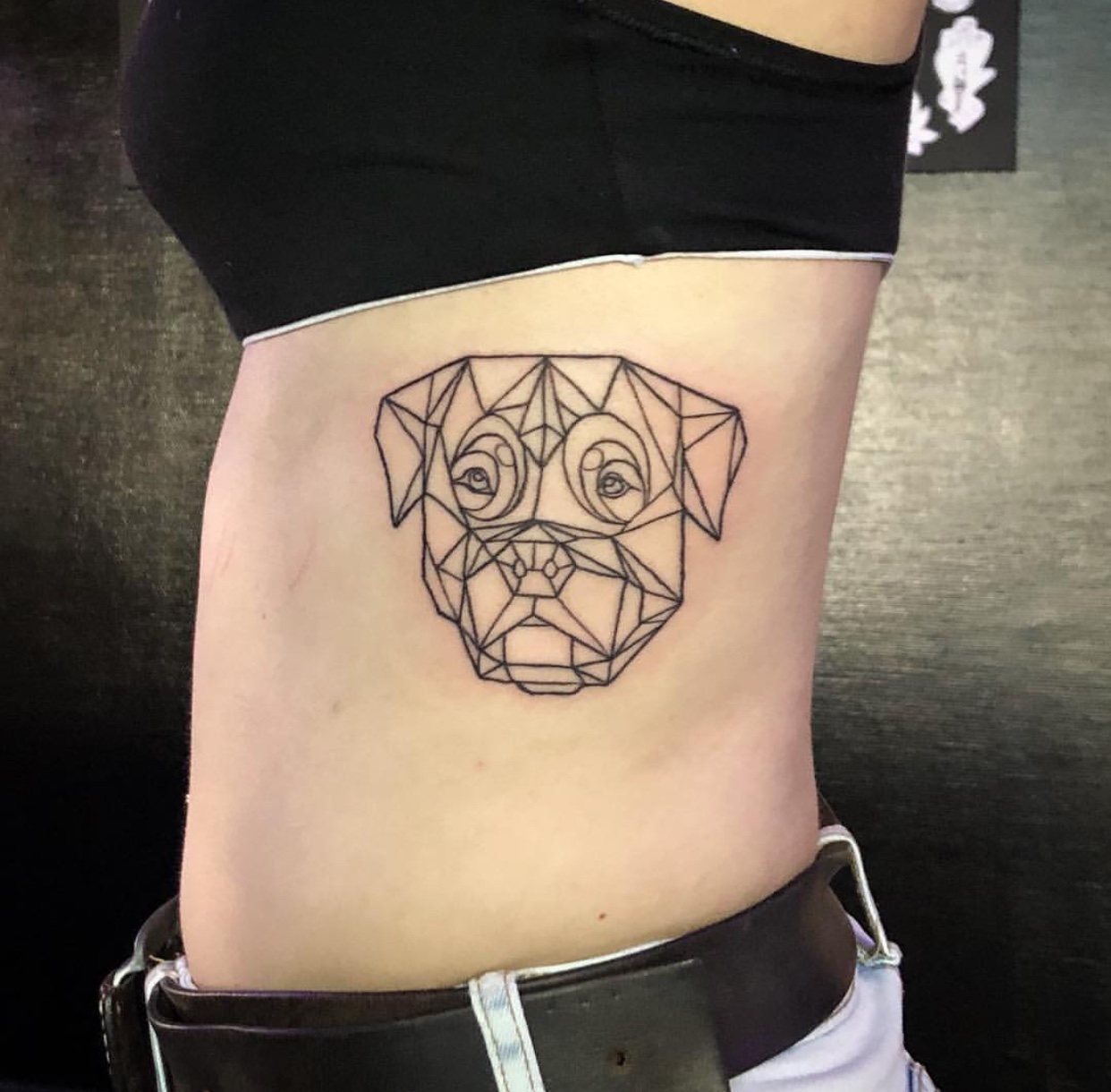 geometric face of Rottweiler tattoo on the side of the girls body