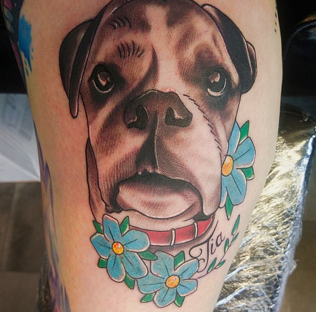 realistic face of a Boxer and with flowers tattoo on the thigh