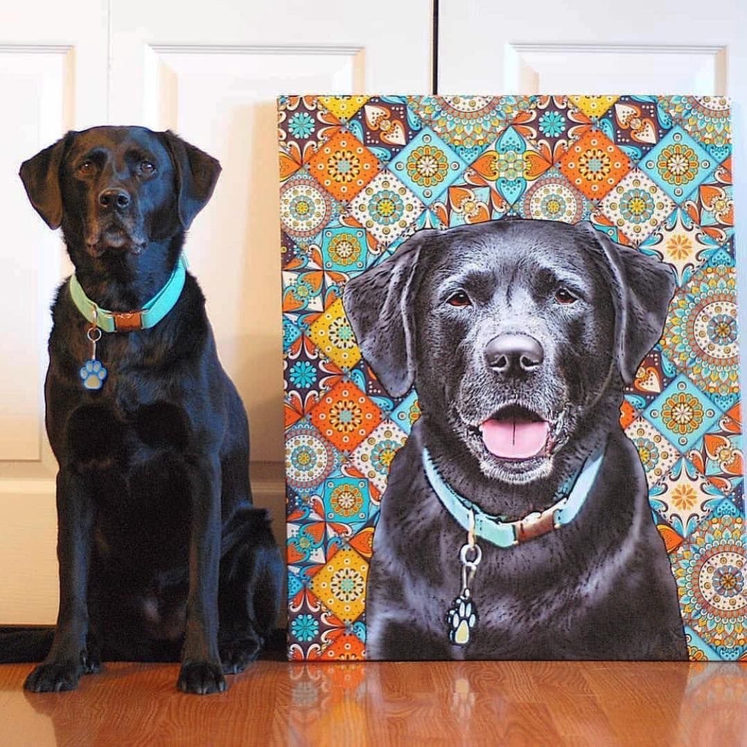 black Labrador Retriever sitting on the floor beside a large painting with his face
