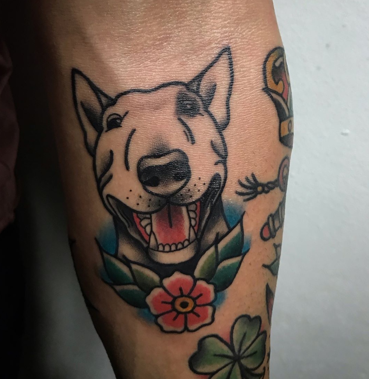 smiling Bull Terrier with flowers tattoo on the forearm